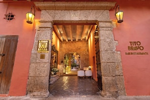 L’entrée de l’hôtel El Marques se distingue par une arche en pierre, deux chaises blanches et une enseigne indiquant le bar-restaurant Tito Bravo.