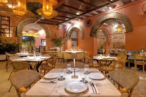 Een restaurant met marmeren tafels, rieten stoelen en warme verlichting.
