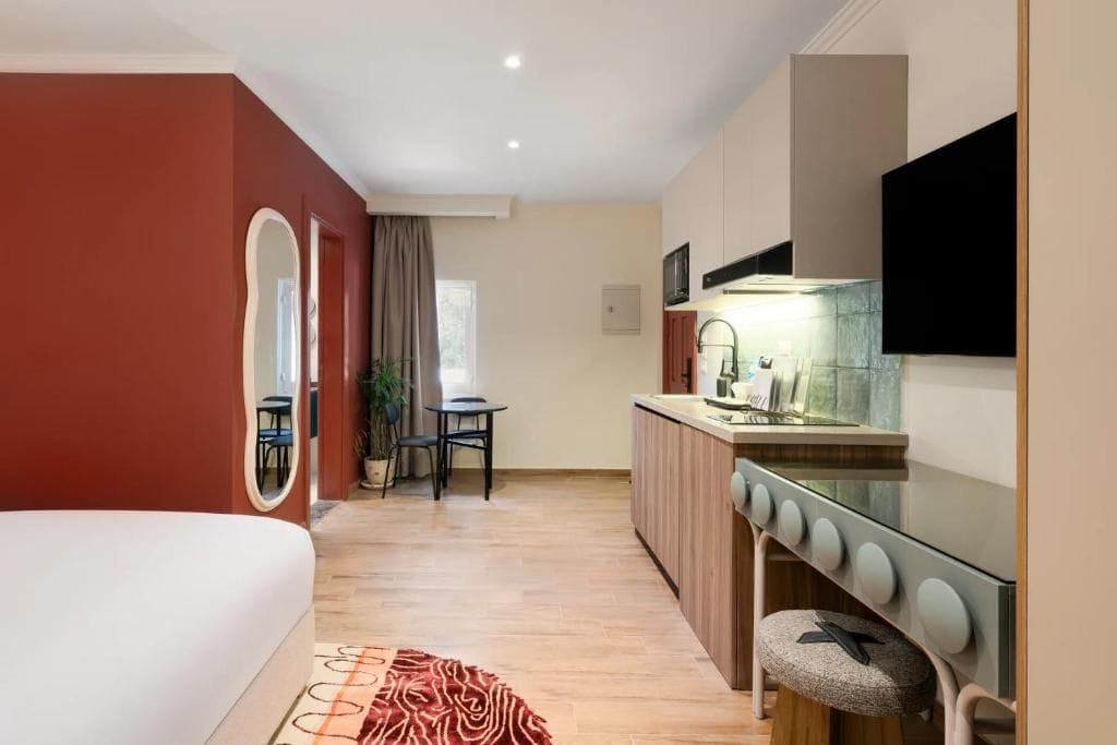 Ein kompaktes Hotelzimmer mit einer Küchenzeile, einem Essbereich und einem großen Bett.