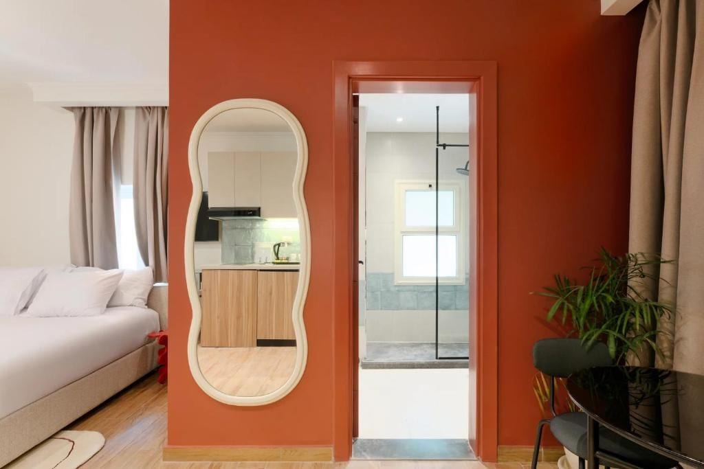 Une chambre à coucher avec un lit, un miroir et une vue sur la cuisine et la salle de bain.