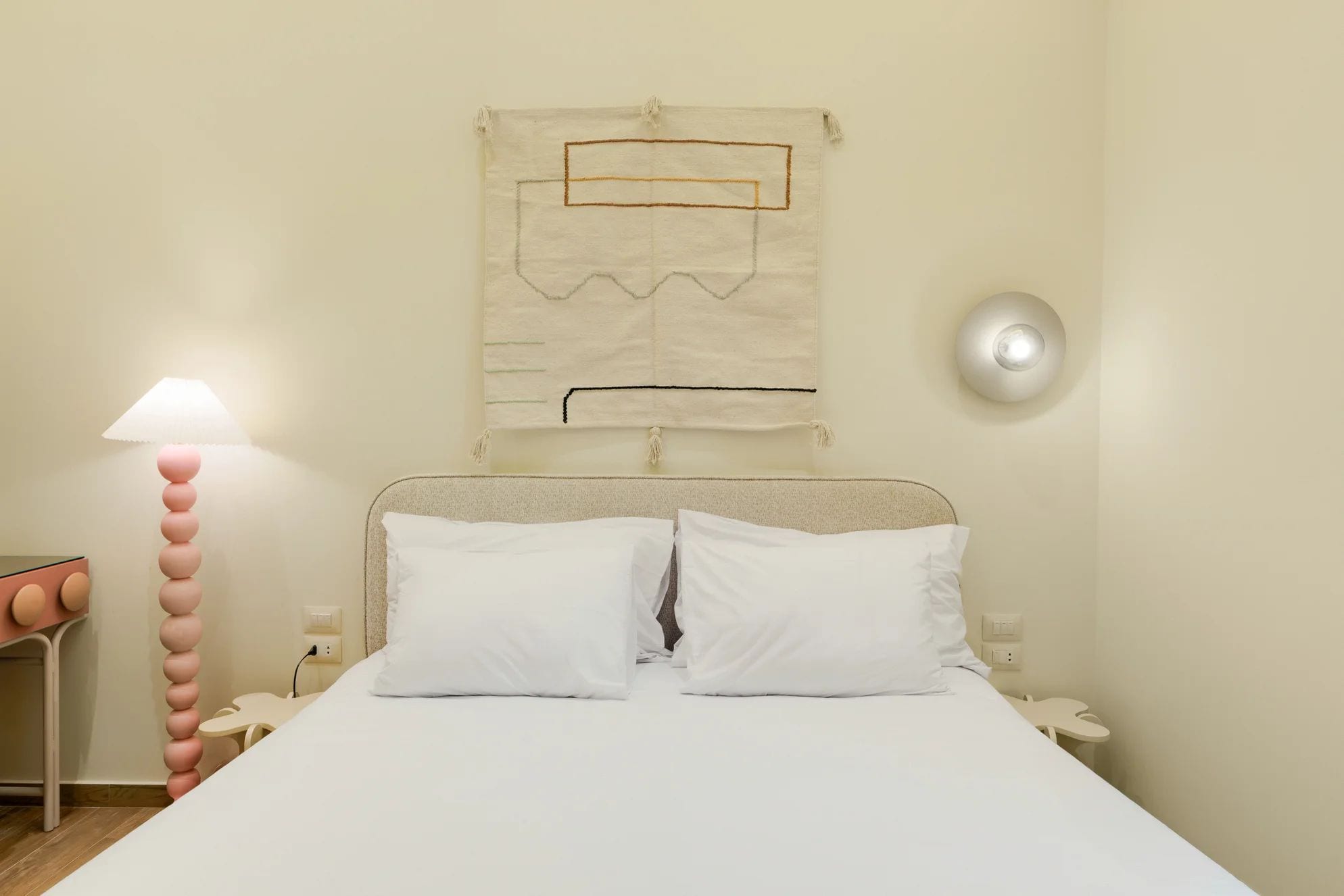 Ein Schlafzimmer mit Bett, Nachttischen, einer Lampe und einer Wandleuchte.
