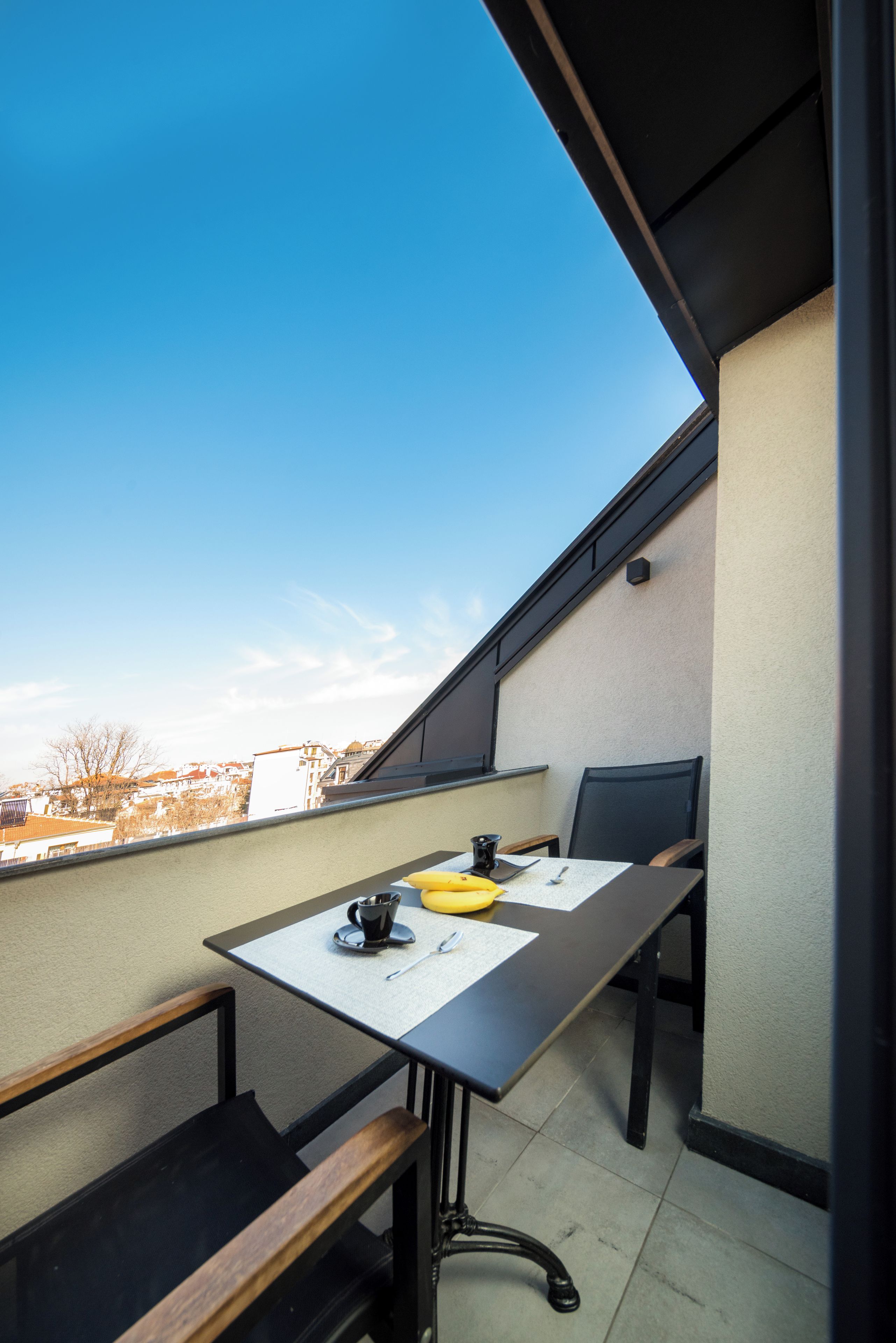 A small balcony with a table, chairs, and a yellow object.