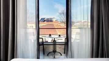 Una habitación con cama, una mesa y vista a un edificio con paneles solares.