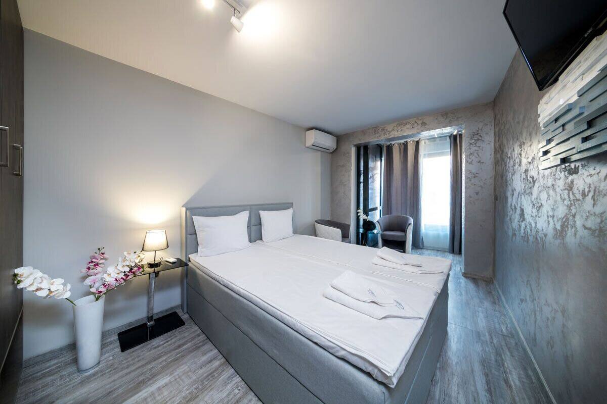 A hotel room with a large bed, bedside tables, a TV, and a window with curtains.