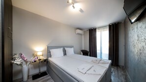 A hotel room with a large bed, a bedside table with a lamp, a chair, and a TV mounted on the wall.