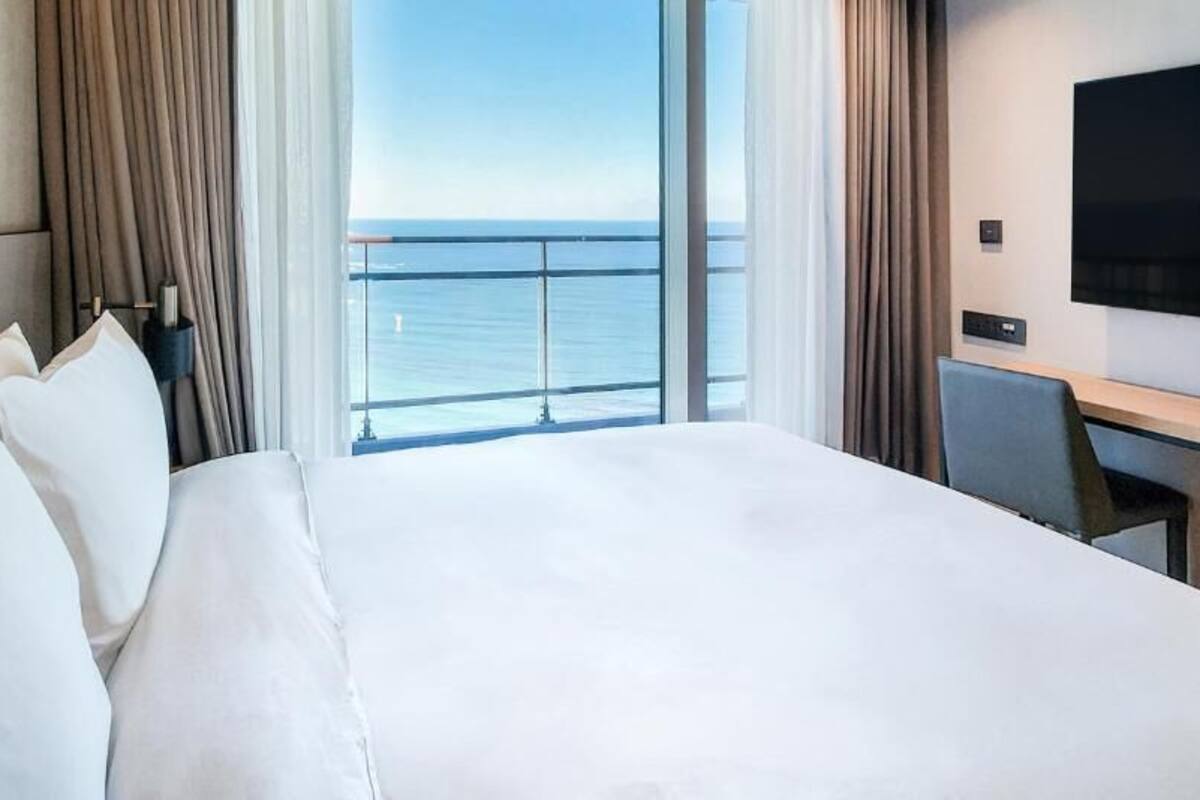 Una habitación de hotel con una cama grande, un escritorio, un televisor de pantalla plana y vistas al océano.