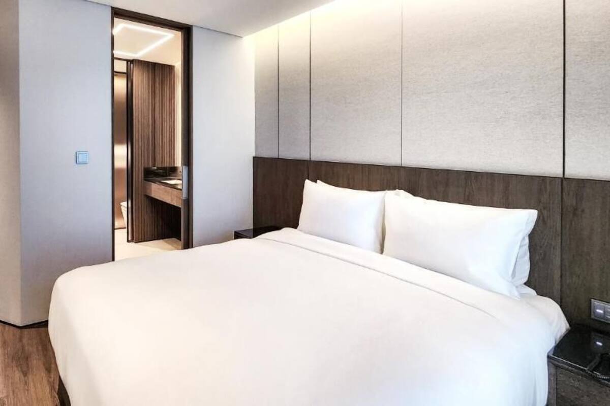 Habitación de hotel con una cama grande, suelo de madera, un armario y un espejo.