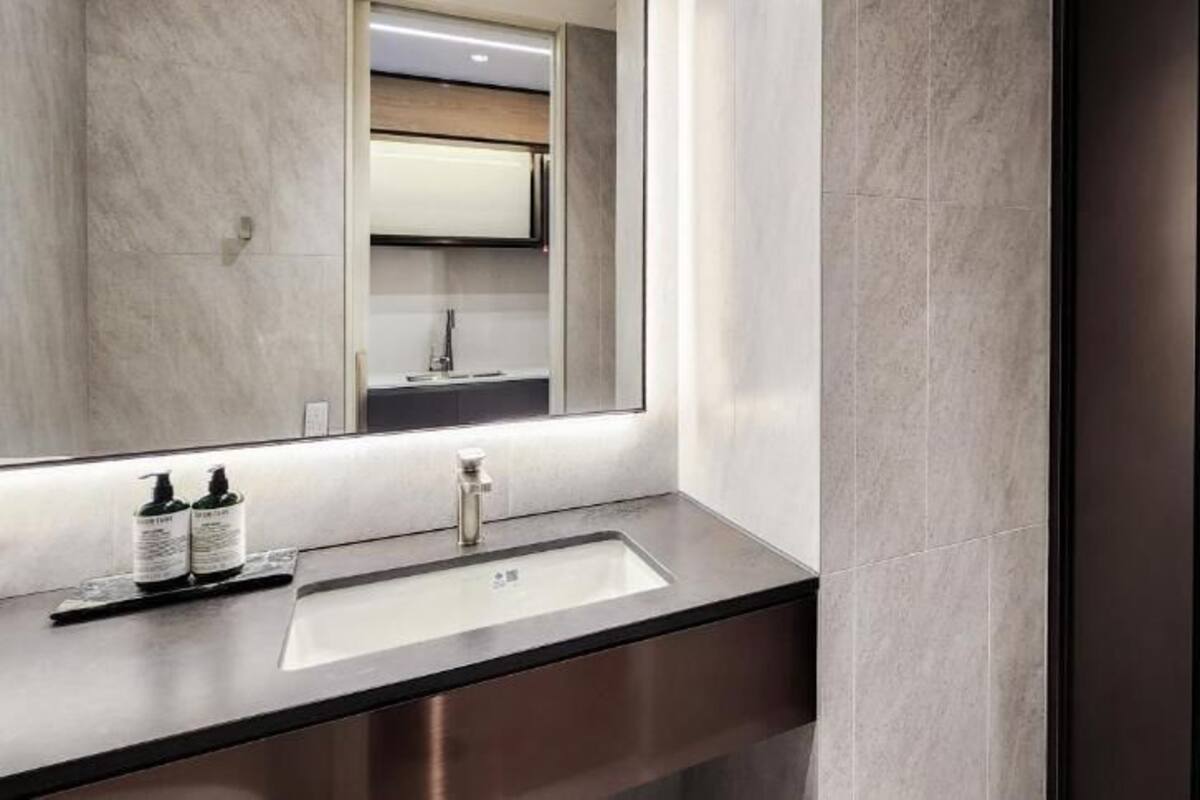 Un baño moderno con un espejo grande, un lavamanos y una zona de ducha.