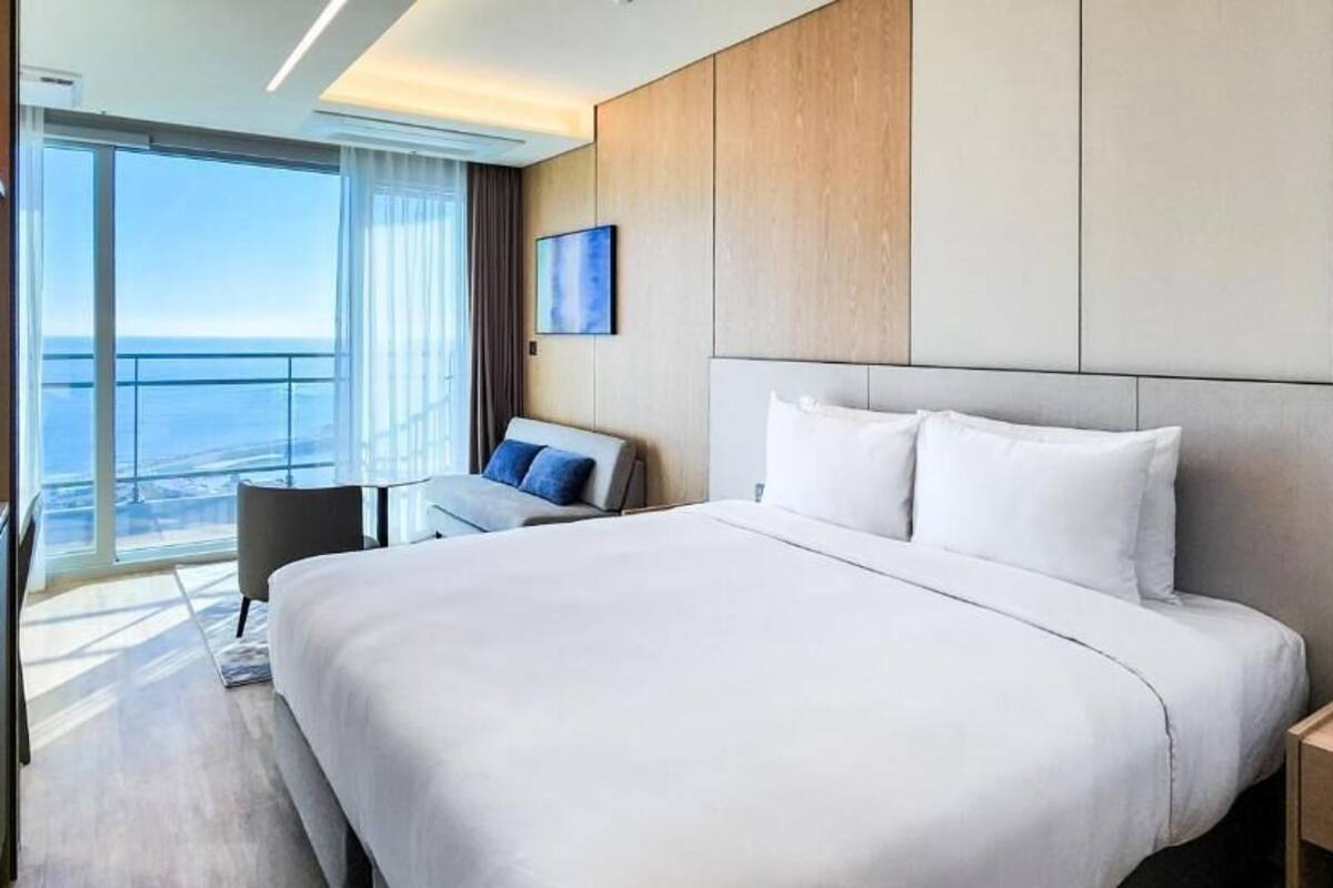 Una habitación de hotel moderna con una cama grande, un escritorio y vistas al océano.