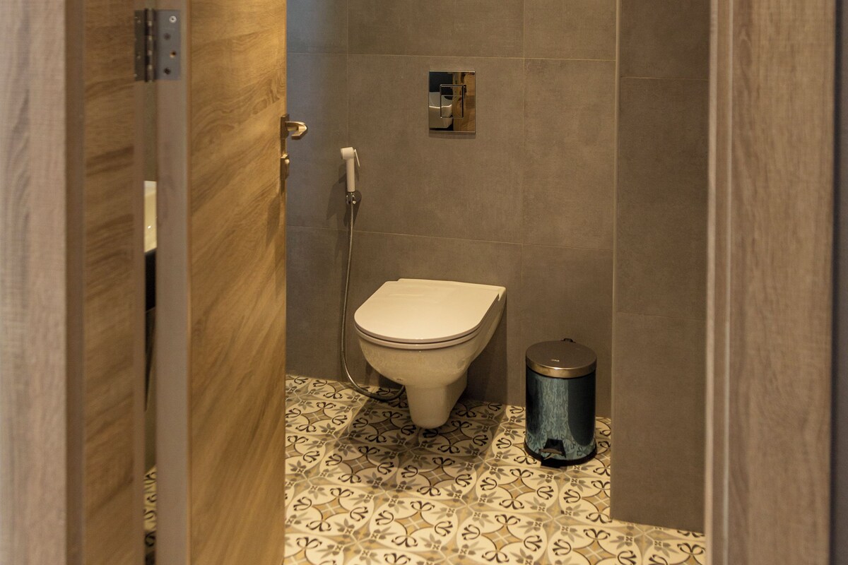 A modern bathroom with a toilet, shower, and patterned floor tiles.