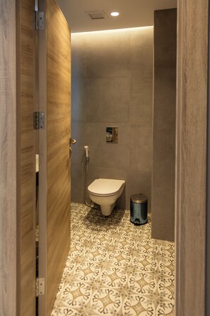 A modern bathroom with a toilet, shower, and patterned floor tiles. - Liv Weibdeh Hotel Suites (Amman)