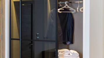 A modern walk-in closet with a mirrored wardrobe, a hanging rack, and neatly folded towels.