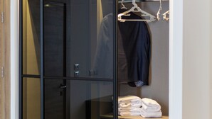 Un dressing moderne, doté d’une armoire à portes miroir, d’une tringle à vêtements et de serviettes soigneusement pliées.