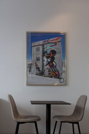 A framed mural on a wall, a table, and two chairs. - Liv Weibdeh Hotel Suites (Amman)