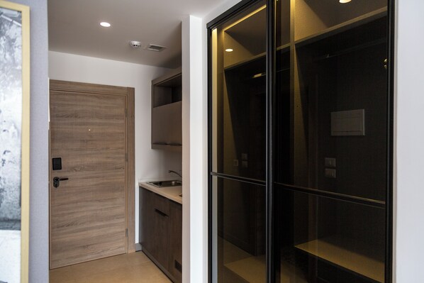 A modern kitchen with wooden cabinets, a sink, and a glass door leading to a dark room. - Liv Weibdeh Hotel Suites (Amman)