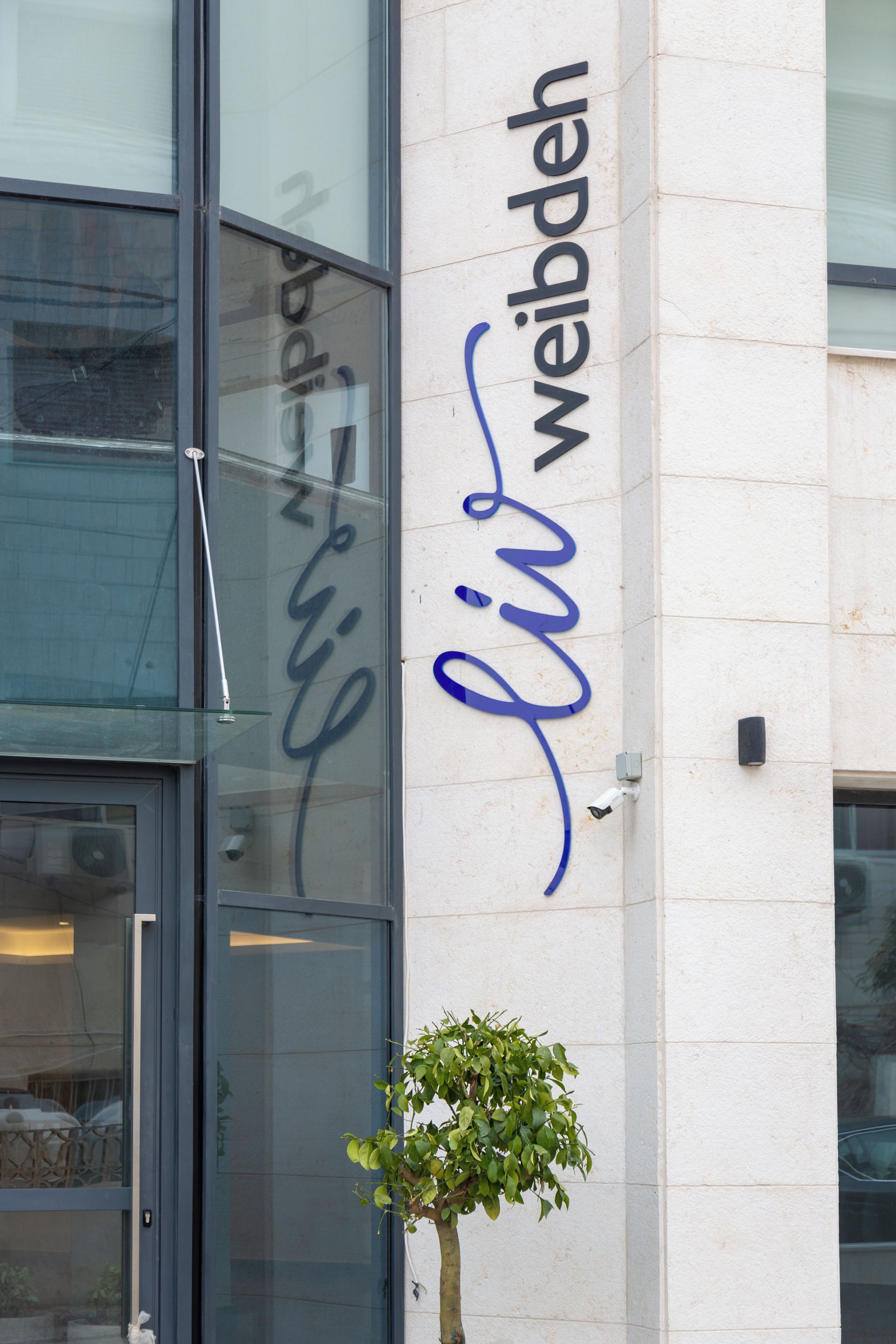 A building with a glass door and a sign that reads "LIV WEIBDEH".