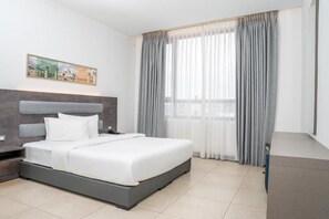 Une chambre d’hôtel moderne avec un grand lit, une table de chevet, un bureau et une fenêtre avec des rideaux.