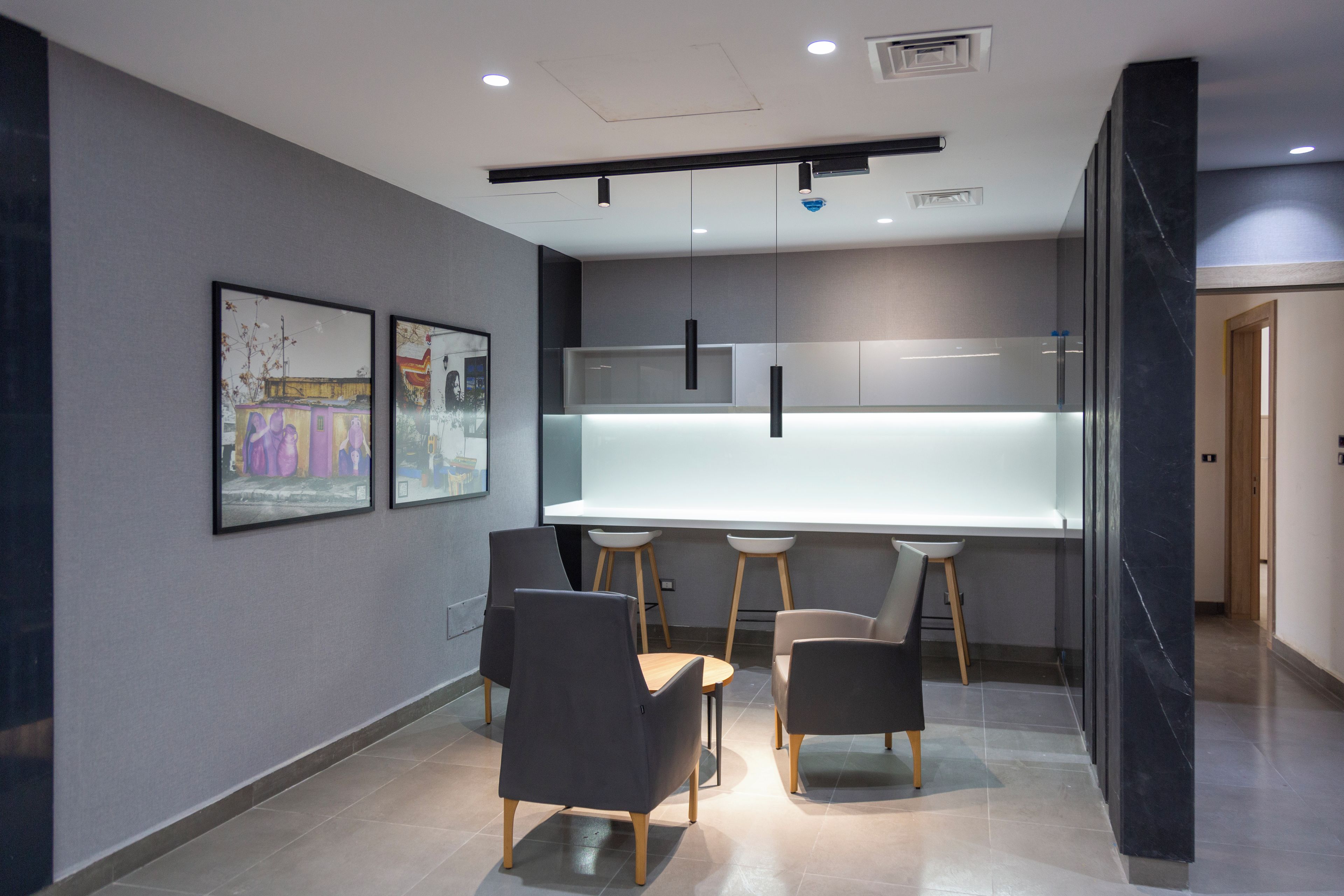 A modern kitchen with a central island, pendant lighting, and a dining area with chairs.
