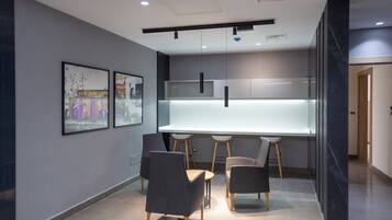 A modern kitchen with a central island, pendant lighting, and a dining area with chairs.