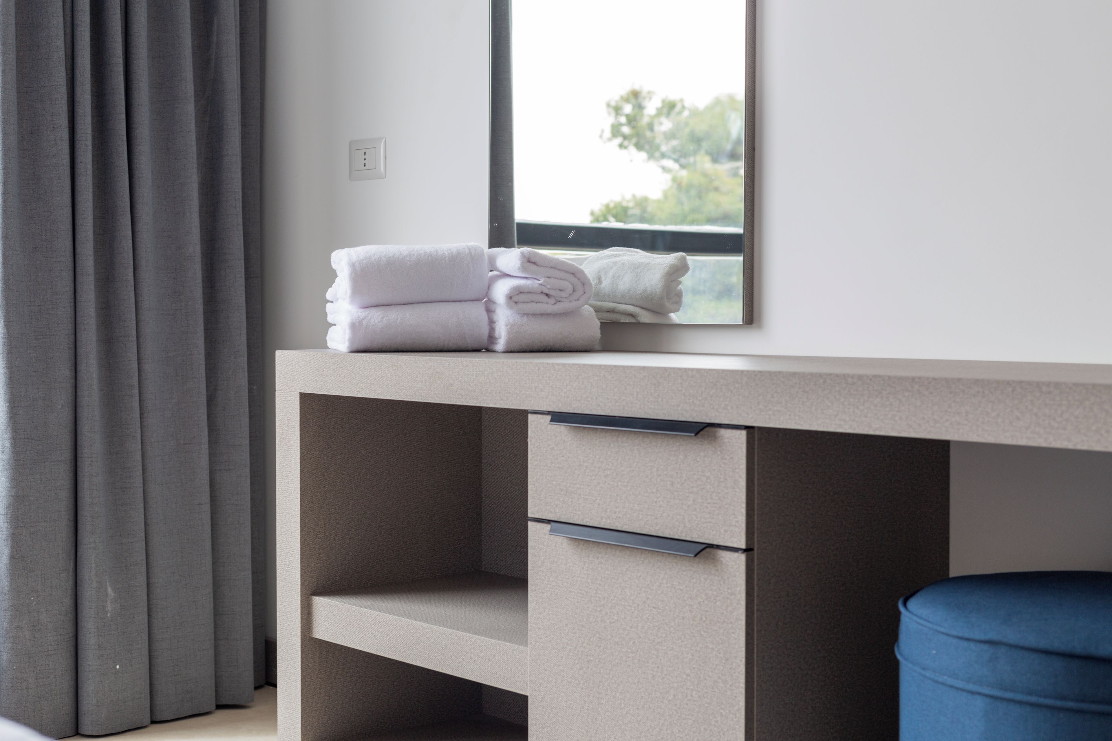 A modern bathroom with a large mirror, a towel rack, and a blue trash bin.