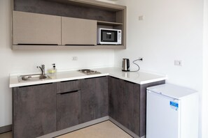 A compact kitchen with a microwave, sink, and a small refrigerator. - Liv Weibdeh Hotel Suites (Amman)
