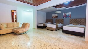 A hotel room with a sofa, two single beds, a chair, and a cityscape painting on the wall. - Suite 94 Hotel Baq (Barranquilla)