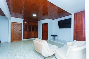 A spacious room with a wooden ceiling, a flat-screen TV mounted on the wall, and two cream-colored sofas. - Suite 94 Hotel Baq (Barranquilla)