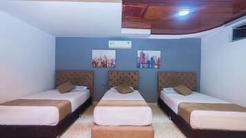 A hotel room with three beds, a ceiling fan, and two wall-mounted air conditioning units.