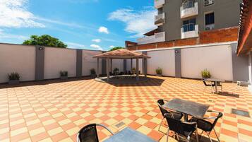 A courtyard with a checkered floor, outdoor seating, and a gazebo.