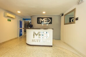A reception desk with 'MED SUITES 94' signage, a mirror, and an emergency exit sign. - Suite 94 Hotel Baq (Barranquilla)