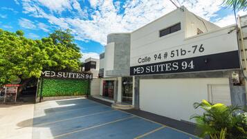 A building with a sign reading "Calle 94 # 51b-76 MED SUITES 94" and a parking lot in front.