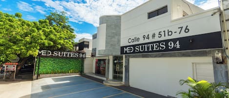 Un edificio con un cartel que dice 'Calle 94 # 51b-76 MED SUITES 94' y un estacionamiento al frente.