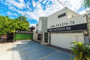 A building with a sign reading "Calle 94 # 51b-76 MED SUITES 94" and a parking lot in front. - Suite 94 Hotel Baq (Barranquilla)