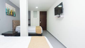 A hotel room with a bed, a TV mounted on the wall, and a painting on the wall.
