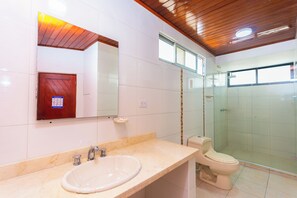 Un baño con lavabo, espejo, inodoro y cabina de ducha de vidrio.