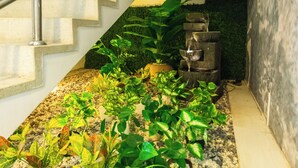 A staircase with a metal handrail, surrounded by potted plants and a small water feature. - Suite 94 Hotel Baq (Barranquilla)