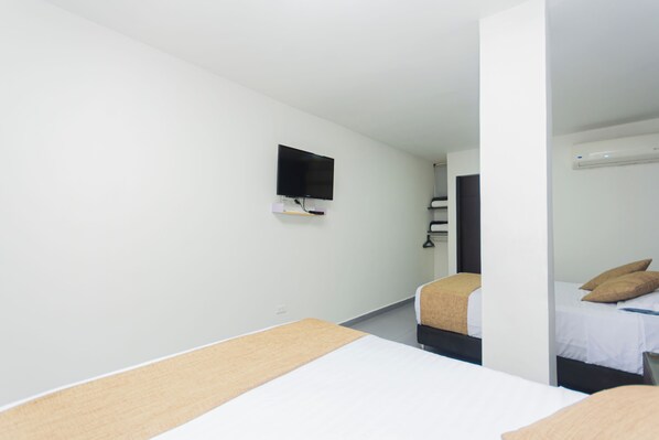 A hotel room with two beds, a flat-screen TV mounted on the wall, and a window. - Suite 94 Hotel Baq (Barranquilla)