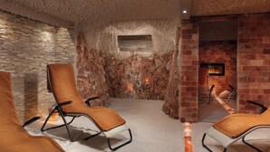 A room with a stone wall, a fireplace, and two lounge chairs. - Grandhotel Nabokov Spa & Wellness (Marianske Lazne)