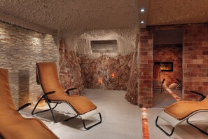 A room with a stone wall, a fireplace, and two lounge chairs. - Grandhotel Nabokov Spa & Wellness (Marianske Lazne)