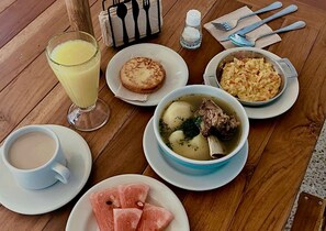 Une table où l’on trouve une variété de plats, notamment une soupe, un verre de jus de fruits et une assiette de viande.