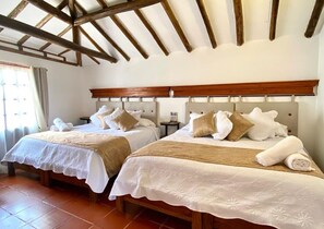 A hotel room with two beds, wooden headboards, and a tiled floor. - Hotel Calle Real (Villa de Leyva)