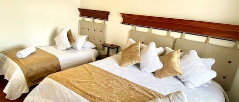 Dos camas dobles con cabeceras, sábanas blancas y almohadas decorativas.