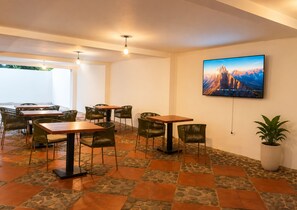 Un espace repas avec des tables et des chaises, un grand tableau accroché au mur et une plante en pot.