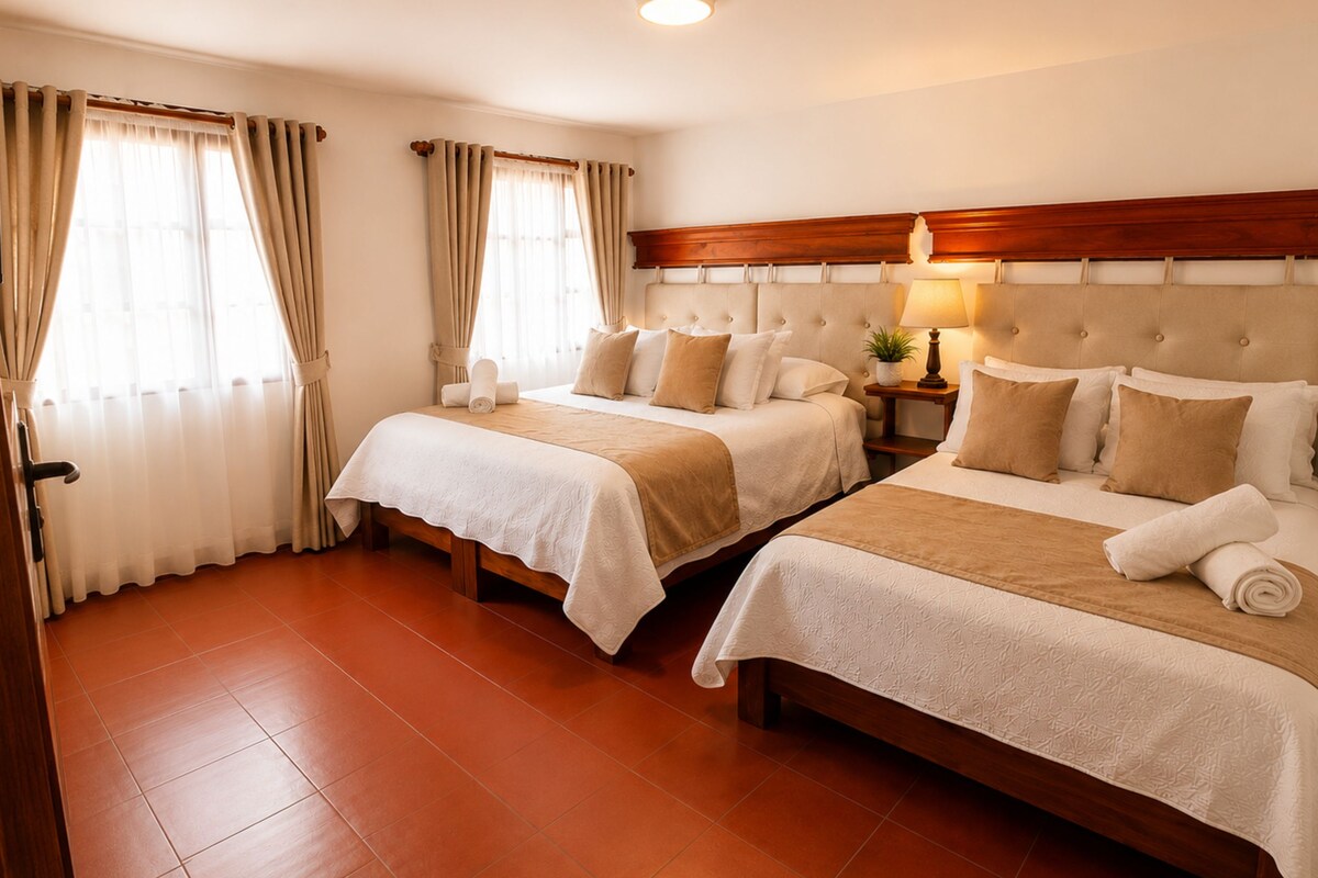 Une chambre d’hôtel avec deux lits, une tête de lit en bois, une table de chevet avec une lampe et une fenêtre avec des rideaux.