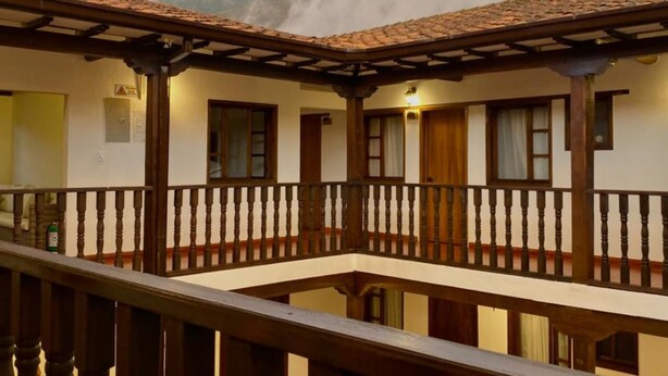 Ein Gebäude mit Balkon, Holellentrailungen und einem Ziegeldach.