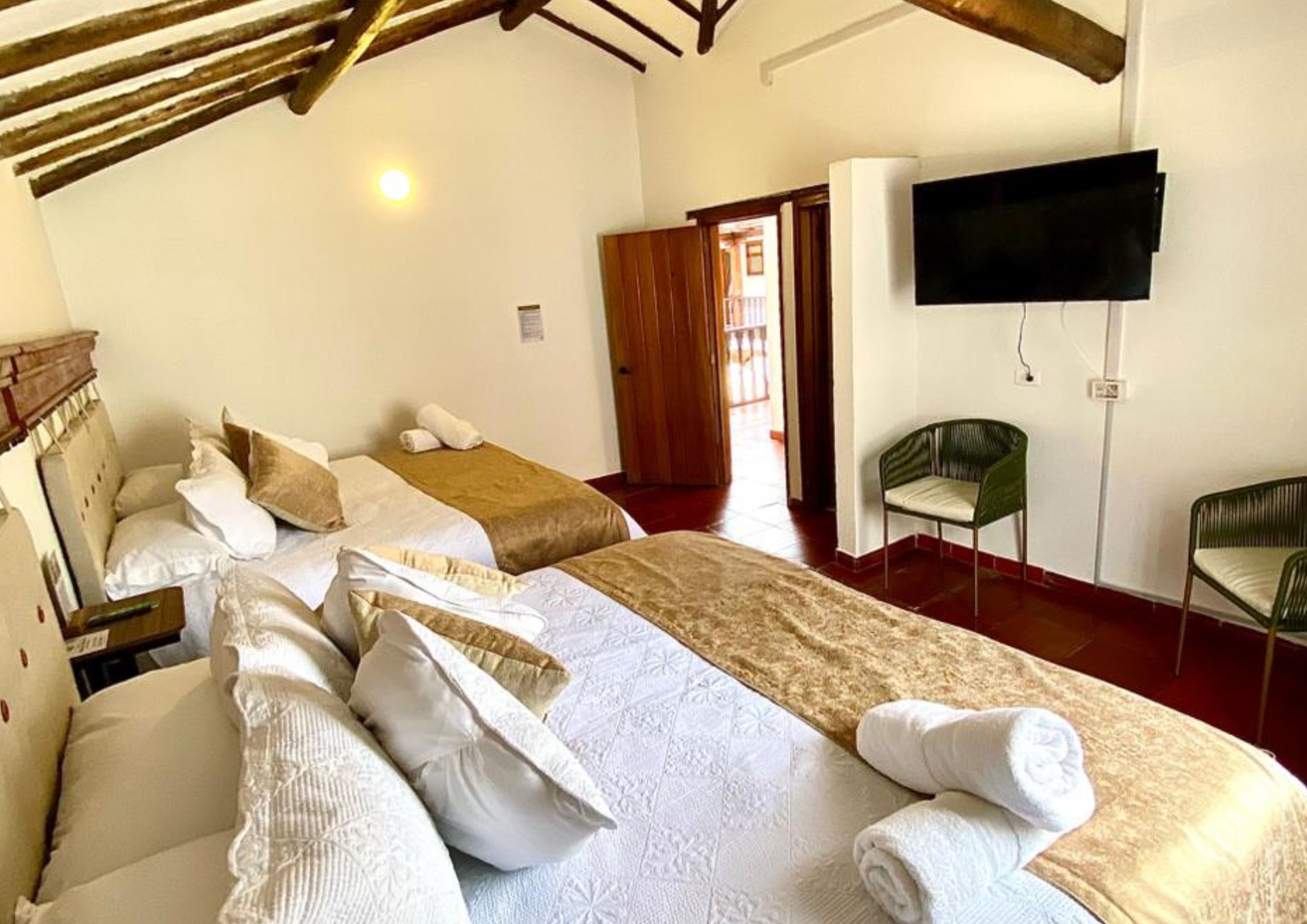 A hotel room with two beds, a TV, a chair, and a door leading to an outdoor area.