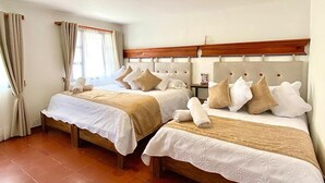 Ein Hotelzimmer mit zwei Betten, jeweils mit einem hölzernen Kopfteil, weißen Leinentüchern und mehreren Kissen.