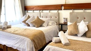 Ein Hotelzimmer mit zwei Betten, jeweils mit einem Holzkopfstück, weißen Laken und beigen Tagesdecken.
