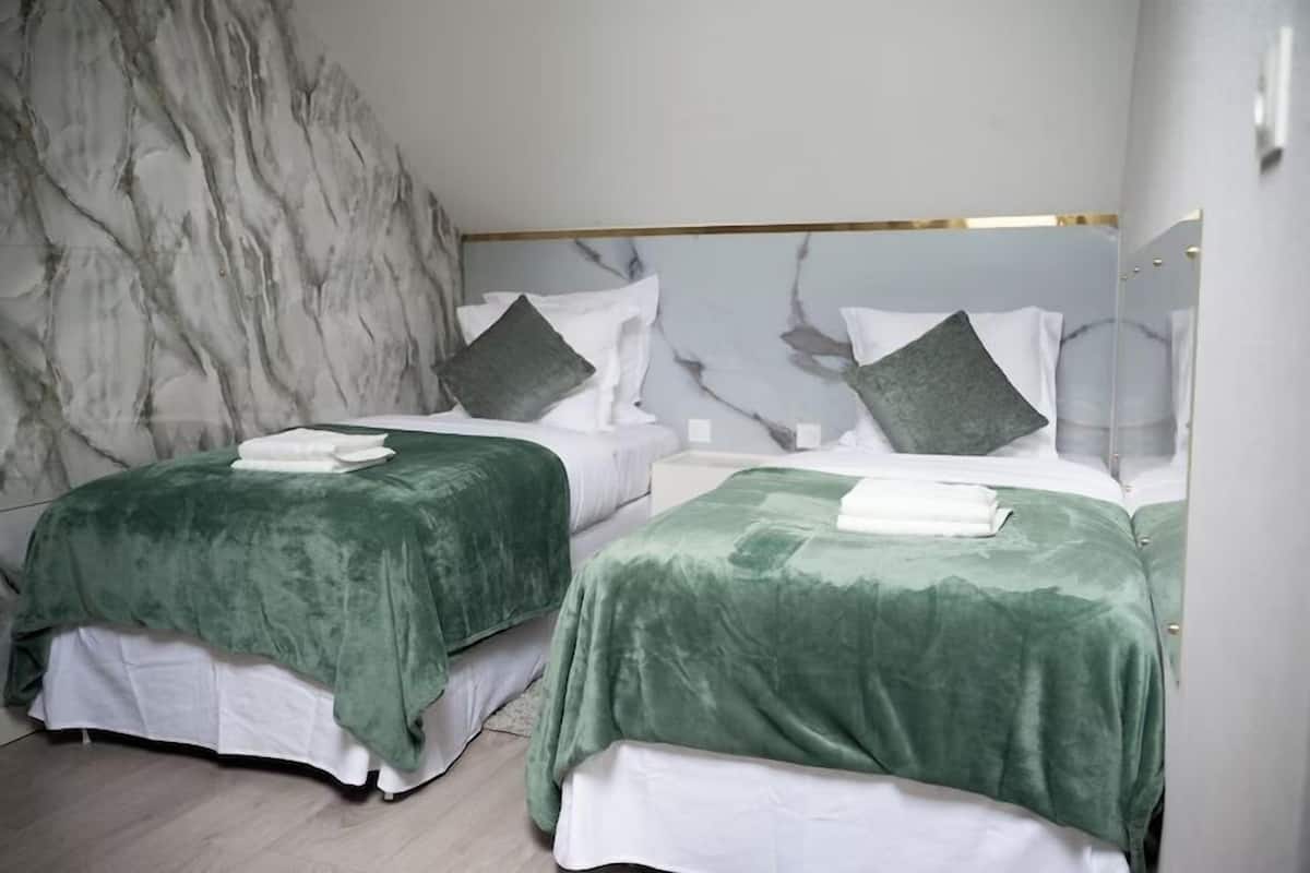 A hotel room with two beds, marble wall, and a modern design.