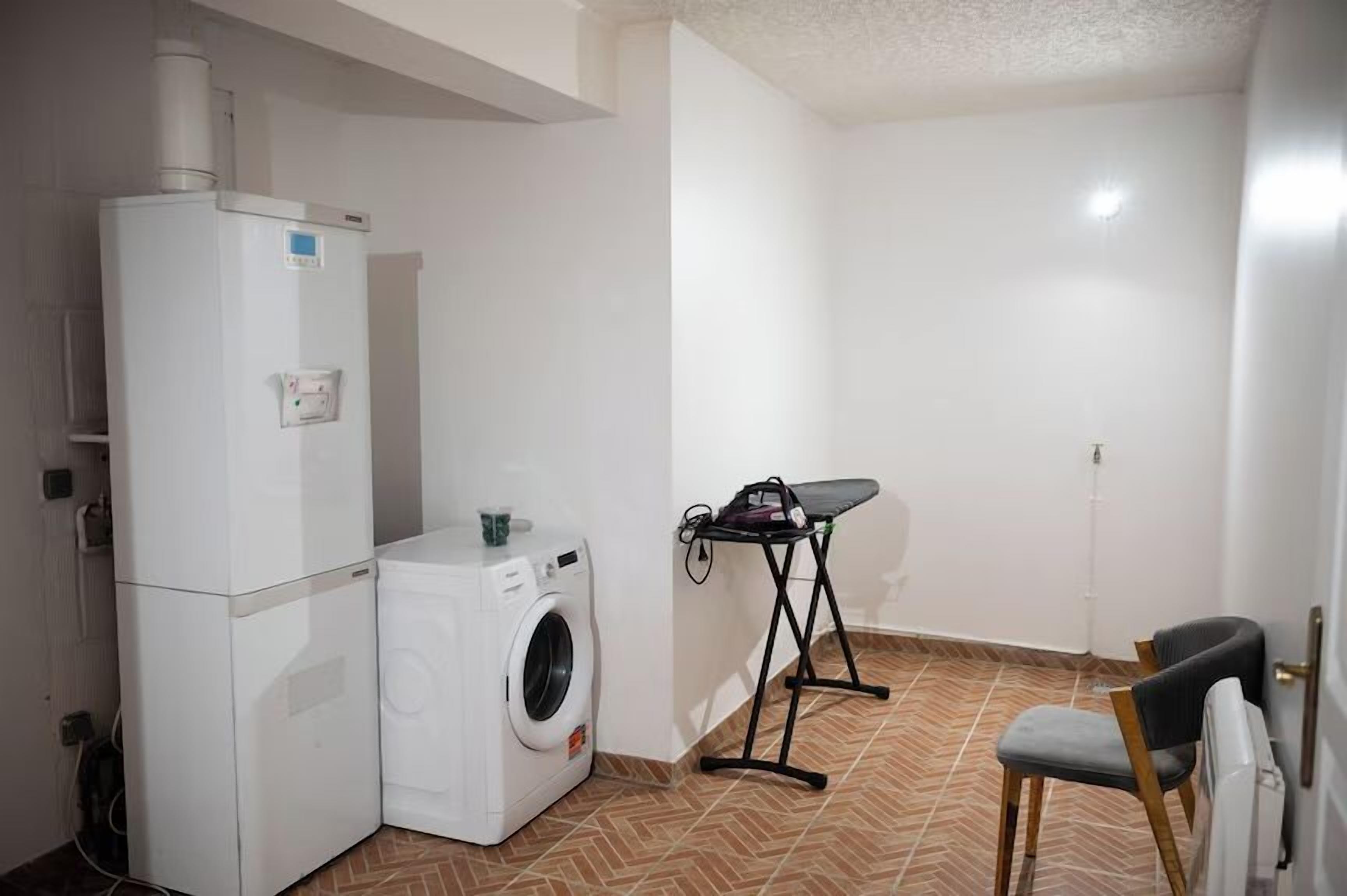 A compact laundry room with a washing machine, a dryer, and an ironing board.